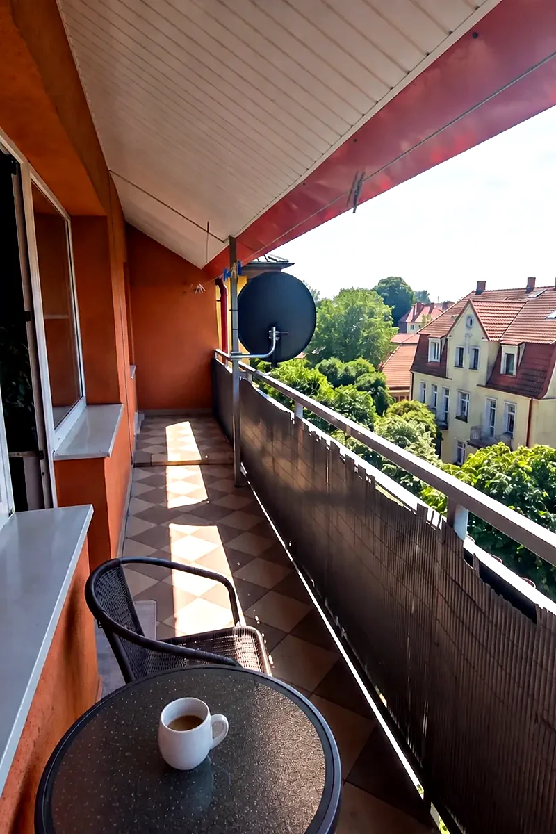 Słoneczny balkon mieszkania ze stolikiem i kawą